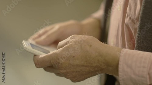 Close up of old man hands text messaging