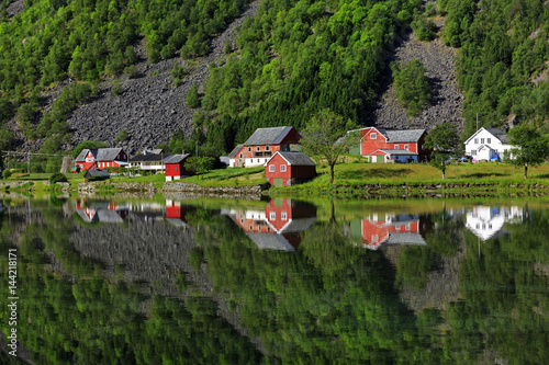 Perfect reflection of some typical norvegia houses into a lake in late spring, Odda, Hardaland, Norway photo