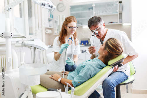 A young woman  seated in the dentist s chair  prepares herself for treatment  her trust in capable hands. Meanwhile  a two dentists discusses her care to ensure a seamless and comfortable experience.