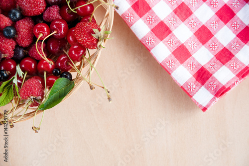 Mixed summer berries in a basket on a table.