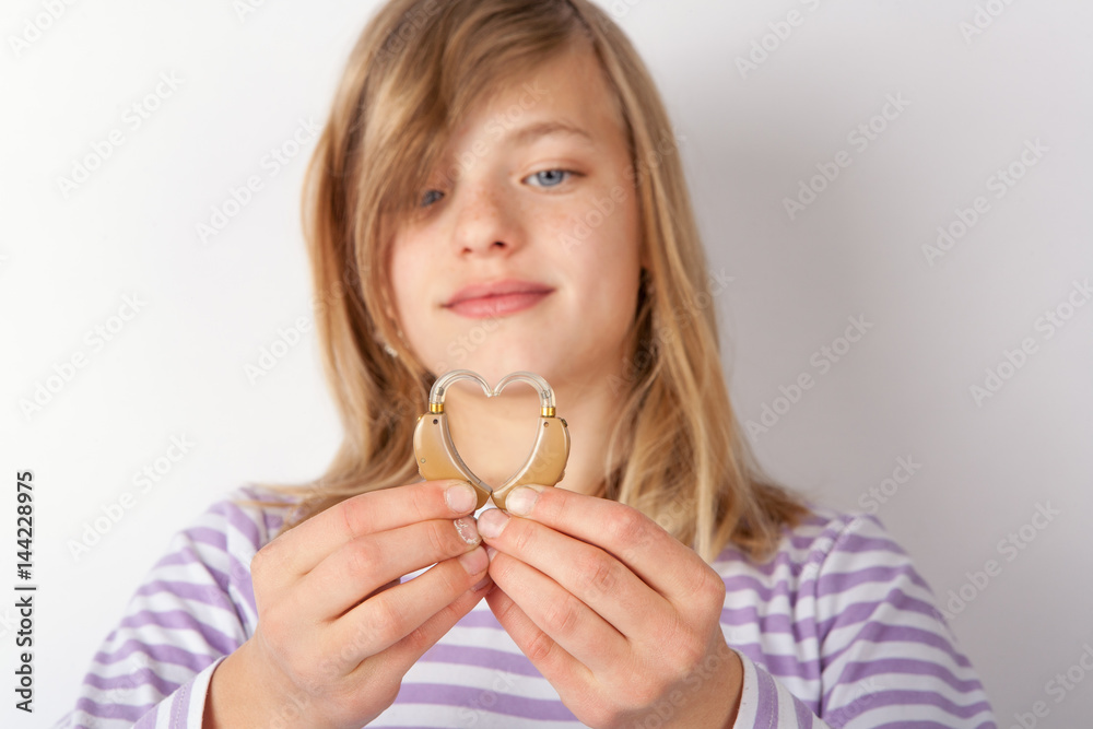 Adorable girl showing a heart shape with two hearing aids