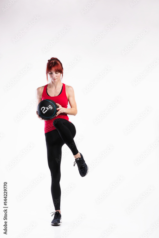 Fitness woman in red tank top holding medicine ball. Studio shot