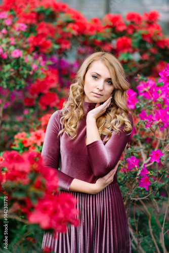 Young pretty woman between red flowers