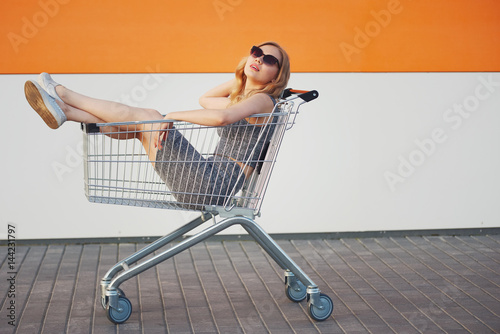 beautiful blonde girl sitting in shopping basket