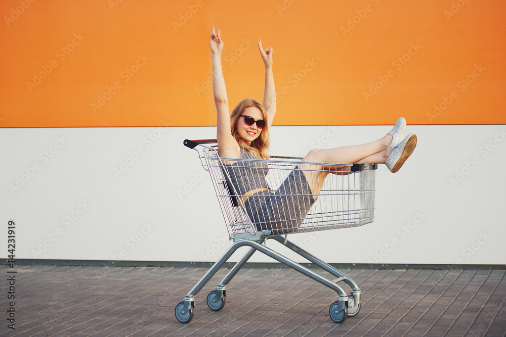 beautiful blonde girl sitting in shopping basket