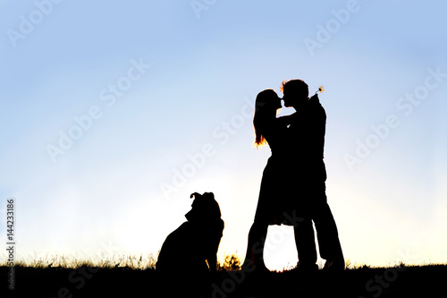Silhouette of Loving Young Couple Hugging at Sunset Outside photo