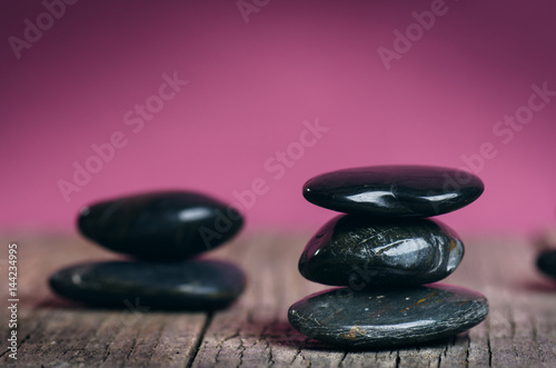 Black stone treatment. Spa and wellness concept. One pink flower on a wooden table and pink background. Lovely flowers. Festive greeting card. Pastel color.. Spring.