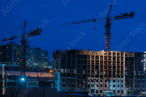 Night construction of an apartment house made of bricks using a crane. The base of the apartment house.
