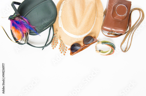 Holiday/travel background. Hipster stuff. Green cross bag, straw hat, retro brown sunglasses, colorful headband, retro camera, boho bracelet and earrings. Flat lay, top view.