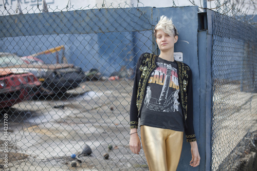 Portrait of young woman leaning against fence