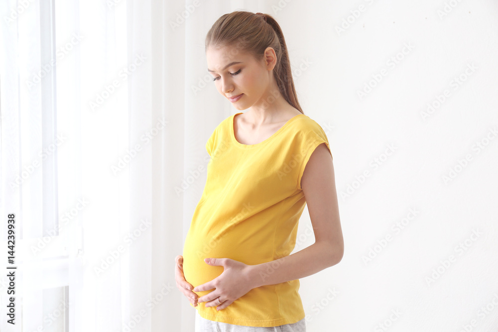 Beautiful pregnant woman standing near window at home Beautiful pregnant woman standing near window at home