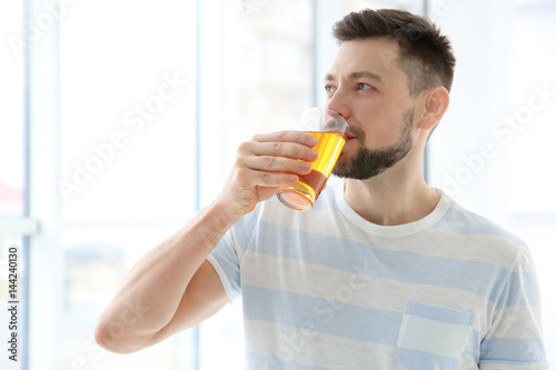 Handsome man with juice standing near window