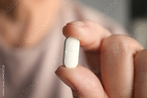Hand of senior woman with pill, closeup