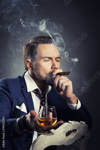 Portrait of man smoking cigar and drinking cognac photo