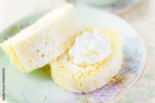 Lemon Cream roll topped with whipped cream and bits of lemon and powdered sugar.