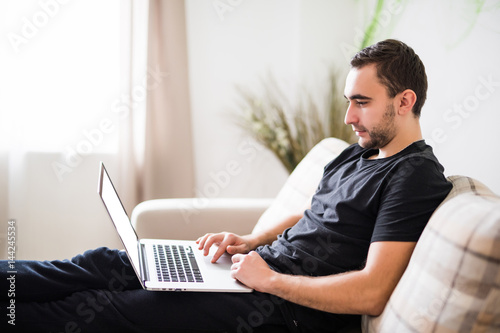 side view Young man relaxing on the sofa with a laptop at home