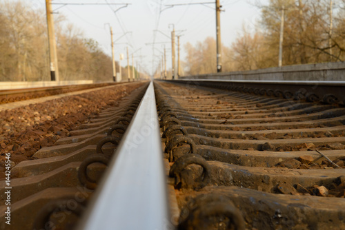 Railway track with sleepers goes into the distance, on the sides-poles for electric wires