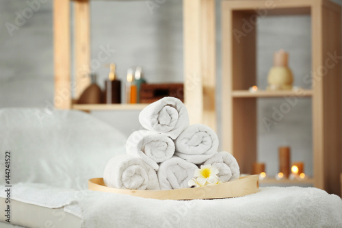 Wooden tray with pile of towels in spa salon