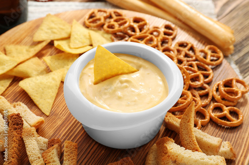 Bowl with beer cheese dip and nacho on wooden stand