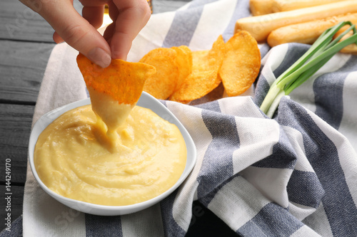 Woman hand dipping nacho in beer cheese dip