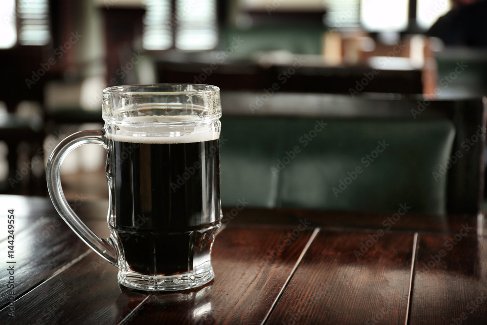 Glass of beer on table in pub Glass of beer on table in pub