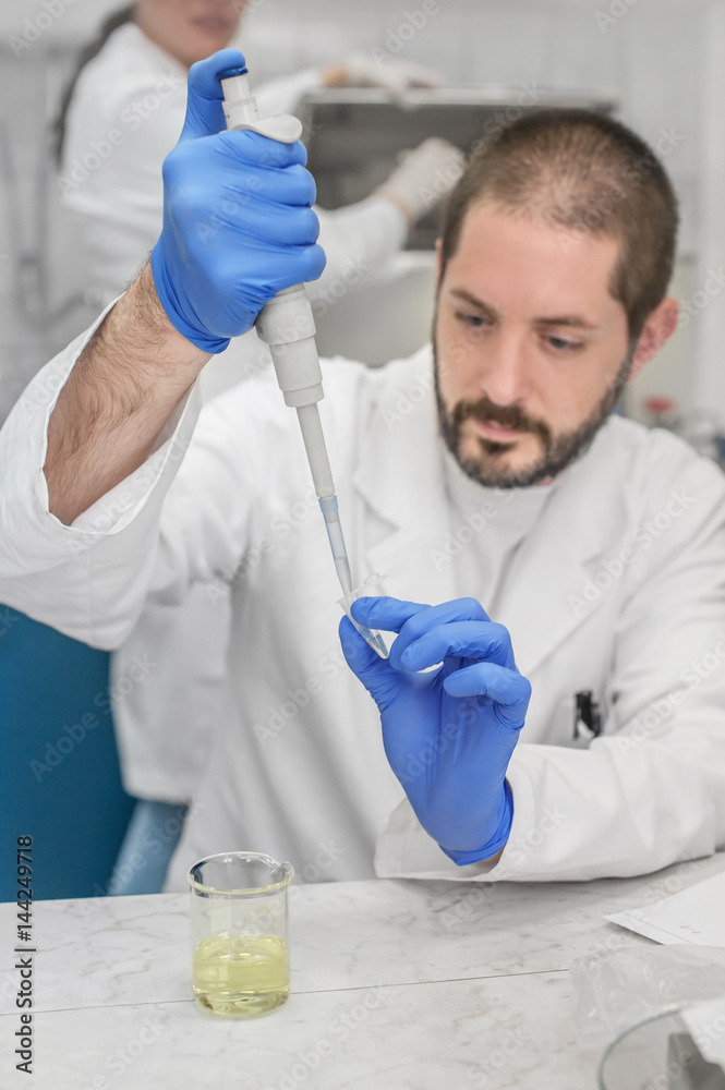 Two scientists in the laboratory filling test tubes with pipette Two scientists in the laboratory filling test tubes with pipette
