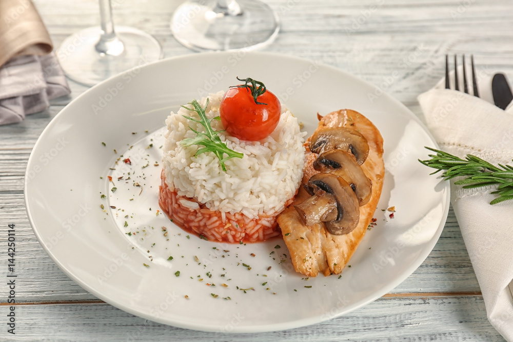Plate with chicken breast and rice on wooden table