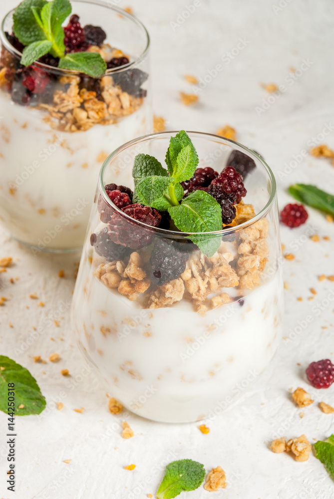 Dietary vegan healthy breakfast. Yogurt and granola with fresh blackberry oranges and mint in a glass. On a white table. Copy space Dietary vegan healthy breakfast. Yogurt and granola with fresh blackberry oranges and mint in a glass. On a white table. Copy space