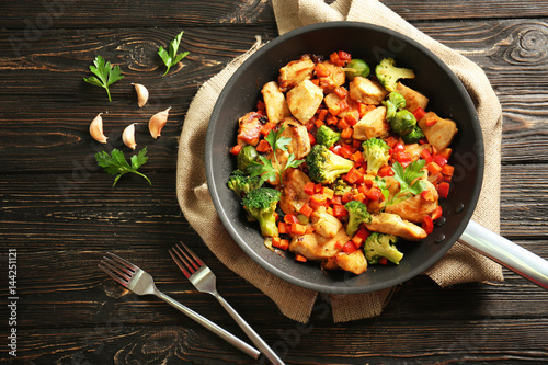 Photo Chicken stir fry with cutlery and spices on table