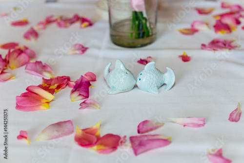 Fototapeta Naklejka Na Ścianę i Meble -  Cute fish saltwort and pepper  on the white tablecloth with rose petals