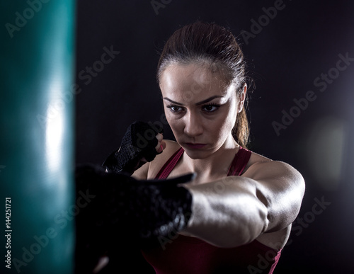 Studio shot of female boxer punching a boxing bag.