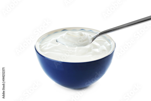 Tasty yogurt in bowl with spoon on white background