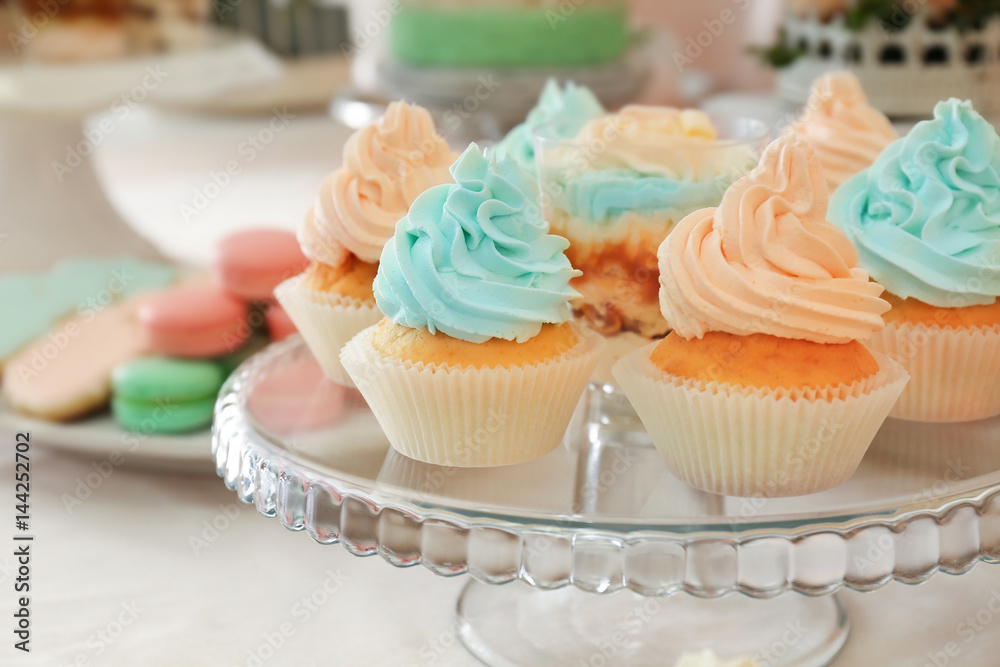 Glass stand with tasty cupcakes on table
