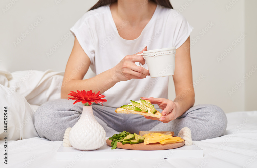 Cropped shot of woman in drinking tea and eating sandwich Cropped shot of woman in drinking tea and eating sandwich