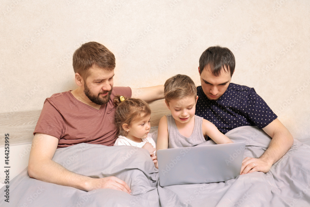 Male gay couple with children resting in bed at home