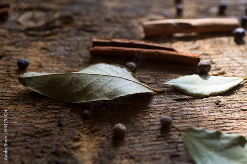 Laurel leaves, cinnamon sticks and juniper berries on wood