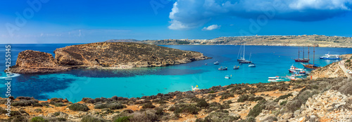 Comino, Malta - Panoramic skyline view of the beautiful Blue Lagoon on the island of Comino with sailboats, traditional Luzzu boats and tourists enjoying the mediterranean sea