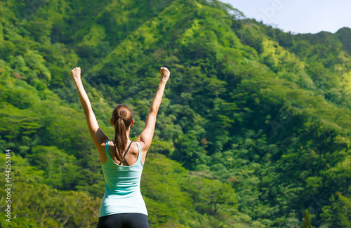 Active healthy lifestyle and fitness goals concept. Fit woman celebrating against a beautiful nature setting. 