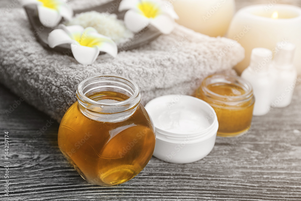 Spa setting with delicious honey and cosmetics grey wooden table Spa setting with delicious honey and cosmetics grey wooden table