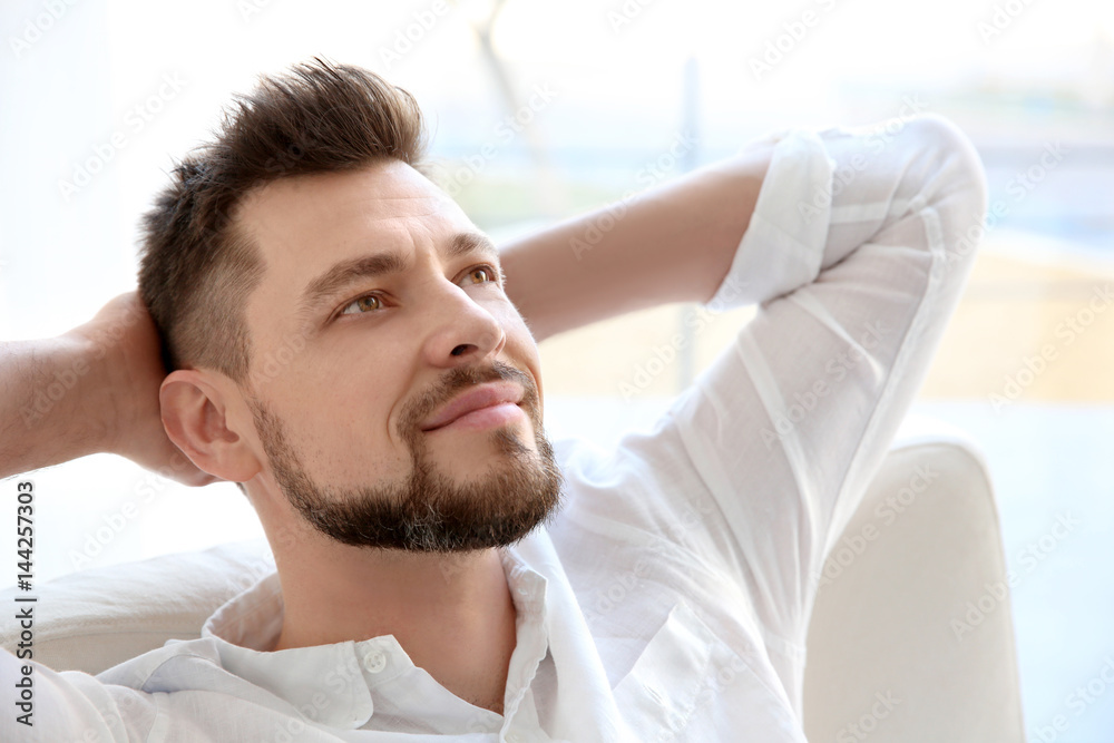 Happy young man resting in armchair at home Happy young man resting in armchair at home