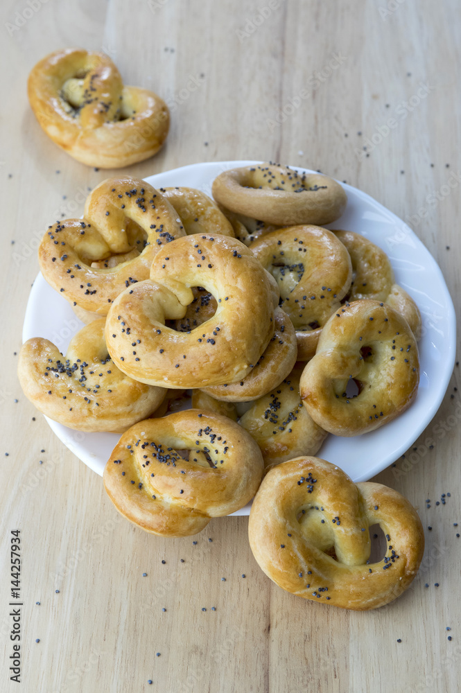 Baked fresh pretzels on white plate, heart and twisted knot shapes, covered with poppy seeds salt and caraway seeds