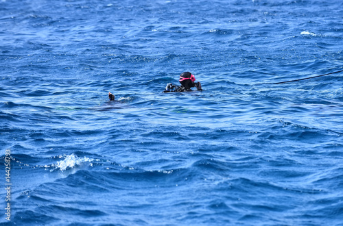 Snorkeling diver or man with diving masks swimming in sea