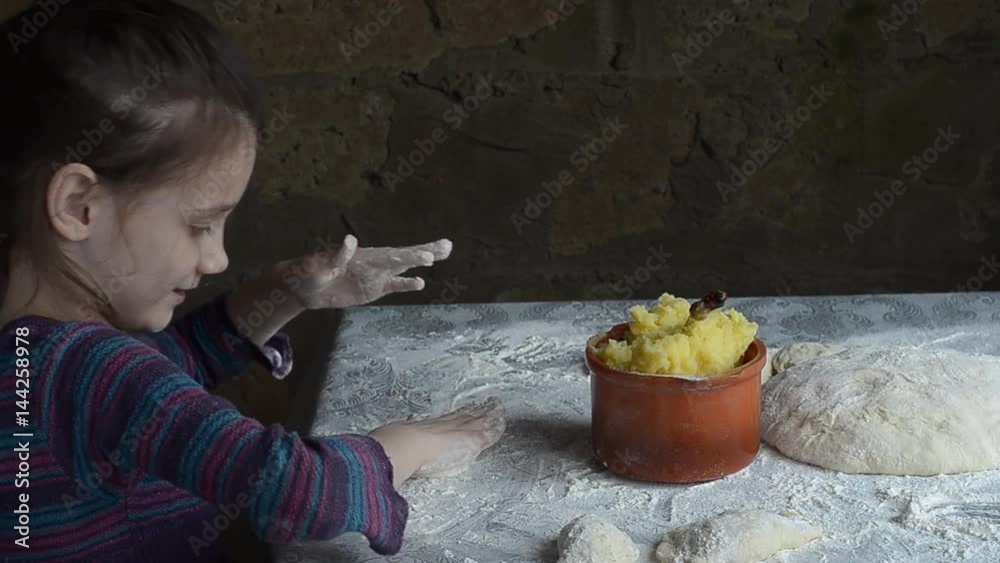 Little girl sculpts patties with potatoes, and sprinkle them with flour. Rustic style. Little girl sculpts patties with potatoes, and sprinkle them with flour. Rustic style.