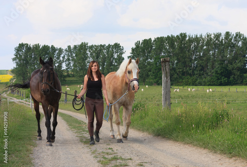 фотографія Young woman walking with  two horses