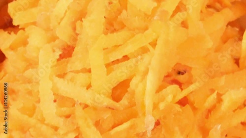 Chopped carrot in white cup on wooden background close up. Ingredient for vegetable salad