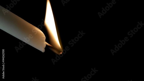 The candle burns and wax drips from it, shot close-up