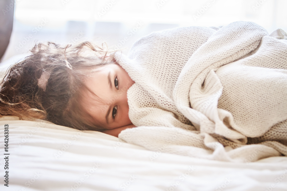 indoor portrait of young child girl wrapped in blanket - obrazy, fototapety, plakaty 