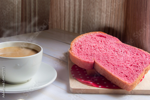 Pink whole wheat bread with espresso coffee on white woodle. photo