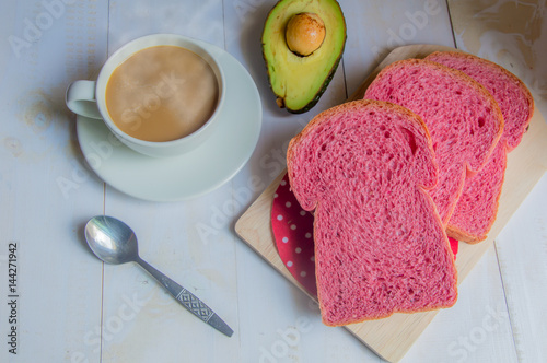 Pink whole wheat bread with espresso coffee and avocado on white woodle. photo