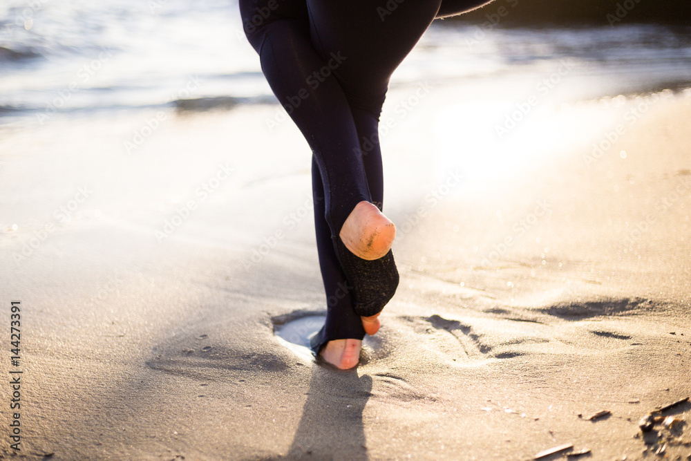 Female feet on the beach. Feet girl in yoga pant, pants, leggings